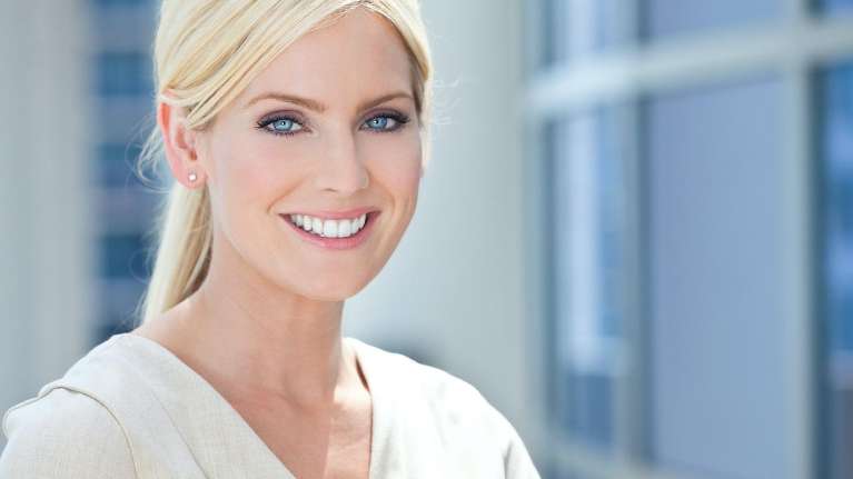 woman with blonde hair and blue eyes smiling