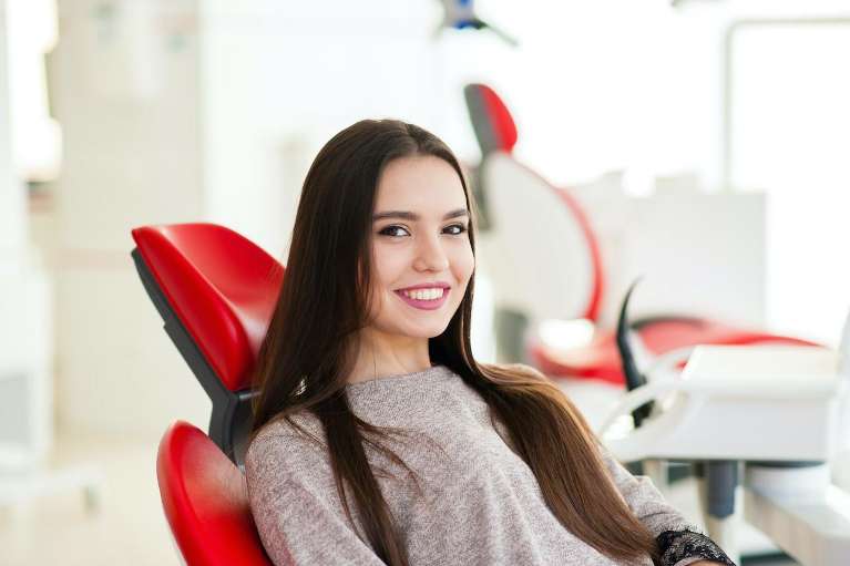 woman sitting in a red dental chair