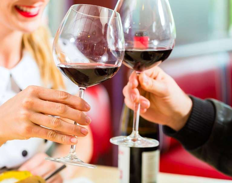 Close-up of hands holding red wine glasses