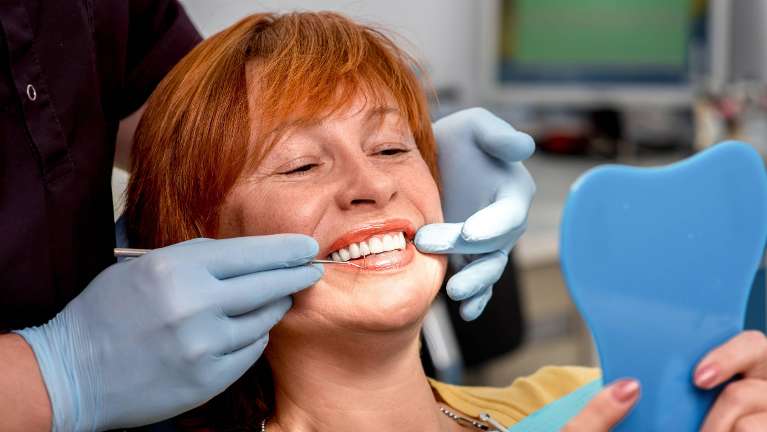 woman in a dental chair while lookin at the mirror