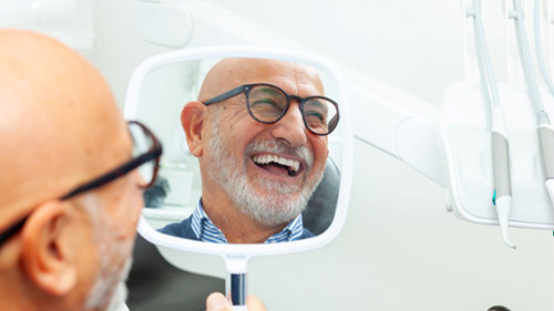 Full mouth reconstruction patient admiring smile in Mesquite, TX